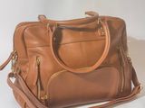 sac à main en cuir beige avec des fermetures éclair et des finitions dorées