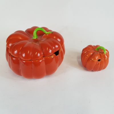 deux petites citrouilles en plastique posées l'une à côté de l'autre sur une surface blanche