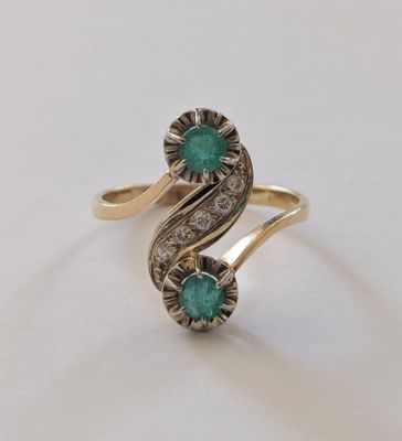 gros plan d'une bague en or avec une pierre verte