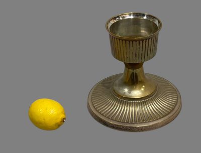 a silver cup next to a lemon on a gray surface