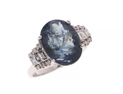 gros plan d'une bague avec une pierre bleue et des diamants