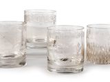 four clear glass tumbles sitting next to each other on a white surface