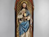 une statue de Jésus tenant une coupe devant un mur
