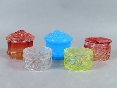 quatre récipients en verre de couleurs différentes posés les uns à côté des autres sur une surface blanche