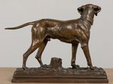 bronze statue of a dog standing on top of a wooden base