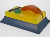 une image représentant une lampe de bureau jaune et bleue posée sur une surface blanche