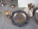 a silver plate on the table next to a silver candle holder