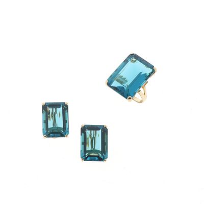 un gros plan sur une paire de boucles d'oreilles et une bague posées sur une surface blanche