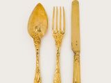 gold plated cutler set with a knife, fork and spoon on a white surface