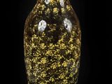 a yellow and black vase sitting on a black surface