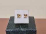 a pair of earrings sitting on top of a marble block