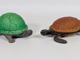 deux figurines de tortues assises l'une à côté de l'autre sur une surface blanche