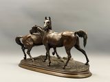 statue en bronze représentant deux chevaux, posée sur un socle en bois, sur fond blanc