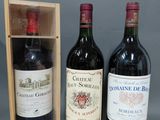 deux bouteilles de vin rouge dans un coffret en bois, à côté d'une bouteille de vin rouge