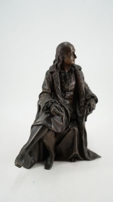 une statue représentant un homme assis sur une chaise