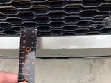 someone is measuring the width of a car ' s grille with a ruler