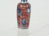 a small red and blue vase sitting on a clear shelf
