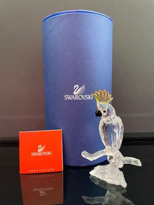 un oiseau en verre posé sur une table, à côté d'une boîte bleue
