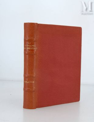 un livre rouge posé sur une table à côté d'un mur blanc