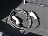 a cable connected to a charger in the trunk of a car