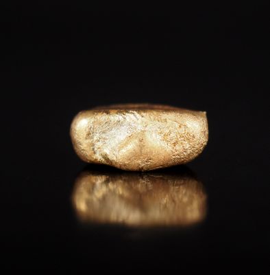 un gros plan d'une bague en or posée sur une surface noire
