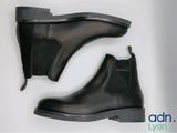 une paire de bottines Chelsea en cuir noir sur fond blanc