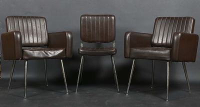 trois fauteuils en cuir marron placés les uns à côté des autres contre un mur gris