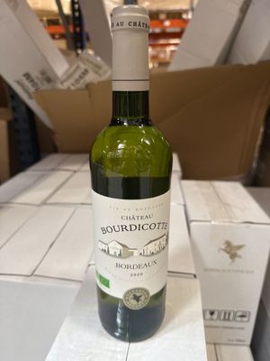 une bouteille de vin posée sur une table, avec des cartons en arrière-plan