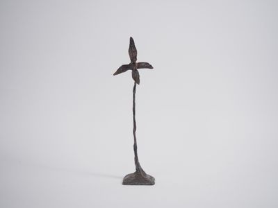 statue of a bird perched on a tree branch in the snow