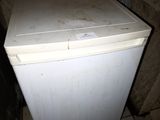 un petit réfrigérateur blanc dans le coin d'une pièce
