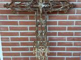 une croix en métal posée par terre près d'un mur de briques