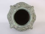 a green vase that has a black hole in it
