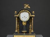 une horloge noire et dorée surmontée d'un oiseau