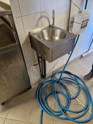 un tuyau bleu raccordé à un lavabo en métal dans une salle de bains