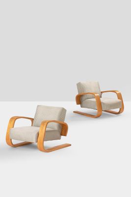 pair of mid - century modern lounge chairs with upholstered backrests