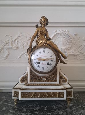 une horloge en or avec une femme assise dessus