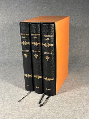 two black books with gold trims are sitting on a gray surface