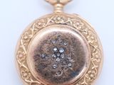 an image of a close up of a gold pocket watch on a white surface