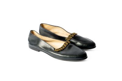 une paire de chaussures noires avec une chaîne sur la pointe