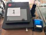une photo d'une caisse enregistreuse posée sur une table, à côté d'un téléphone et d'un ventilateur