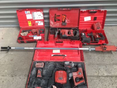 une mallette à outils rouge, contenant des outils, posée par terre