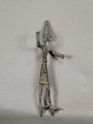 une petite figurine en métal représentant un homme coiffé d'un chapeau
