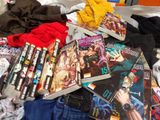 a pile of comic books on a bed next to a pair of jeans
