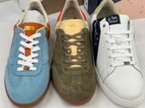 three pairs of sneakers are lined up on a white table