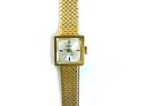 une montre-bracelet en or avec un cadran blanc sur fond blanc