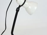 a white table lamp with a black cord on it