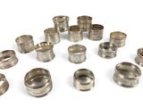 an assortment of silver napkins and napkin rings on a white surface