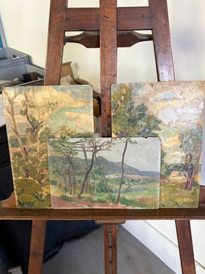 deux tableaux posés sur un chevalet en bois, à côté d'un ordinateur portable