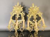 pair of gold plated wall sconces on a mirrored surface
