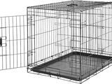 une photo en noir et blanc d'une cage pour chien dont la porte est ouverte